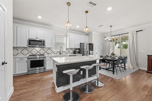 kitchen with white cabinets, appliances with stainless steel finishes, a center island, and dark hardwood / wood-style flooring