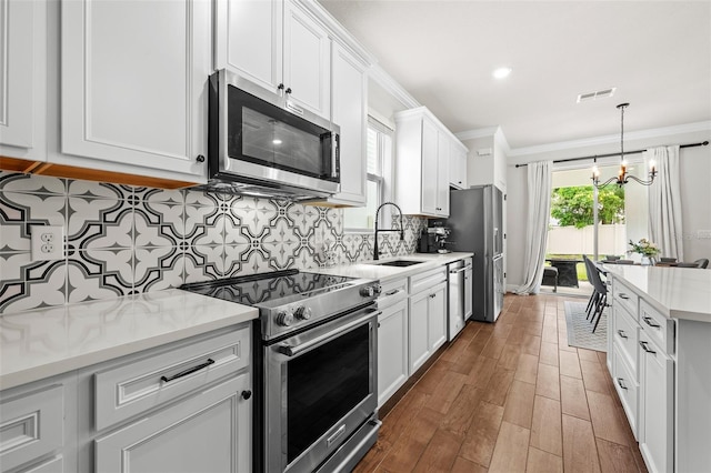 kitchen with white cabinets, stainless steel appliances, an inviting chandelier, and sink