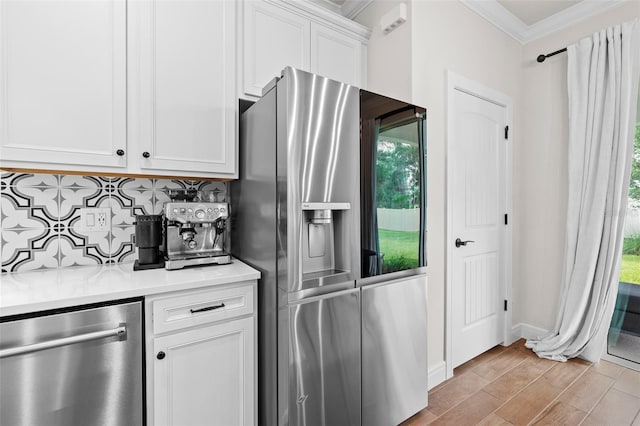 kitchen featuring ornamental molding, white cabinets, stainless steel appliances, and plenty of natural light