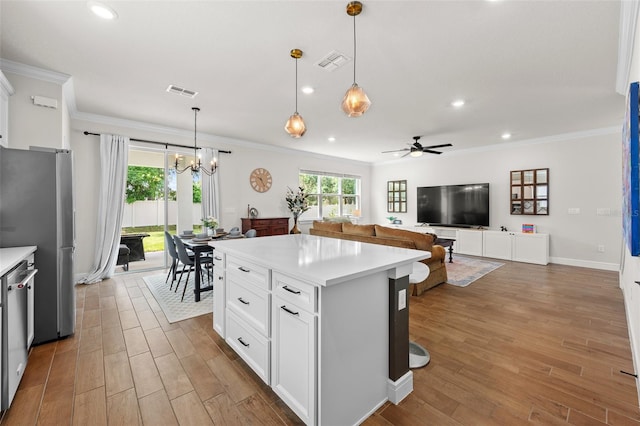 kitchen with white cabinetry, stainless steel appliances, decorative light fixtures, and light wood-type flooring