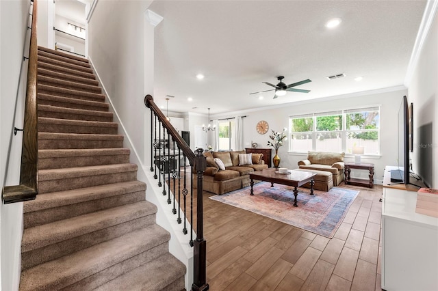 living room featuring ceiling fan with notable chandelier, hardwood / wood-style flooring, and ornamental molding