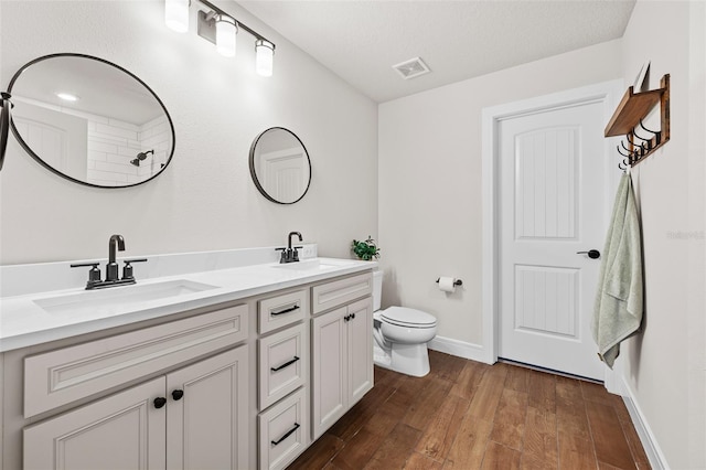 bathroom featuring a textured ceiling, vanity, hardwood / wood-style flooring, and toilet