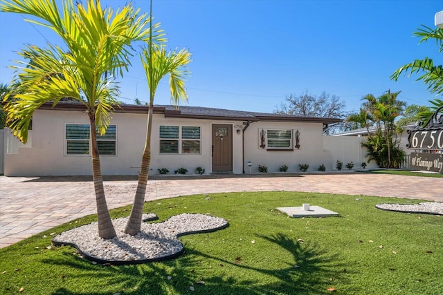 ranch-style home featuring a front lawn, fence, and stucco siding