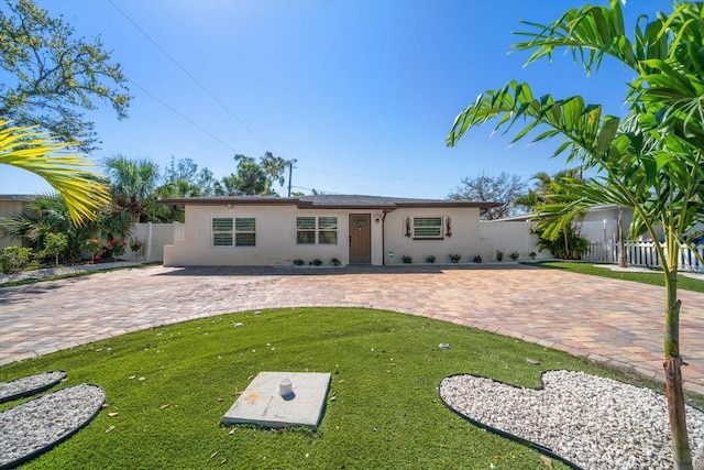 view of front of house with a patio area, fence, a front lawn, and stucco siding