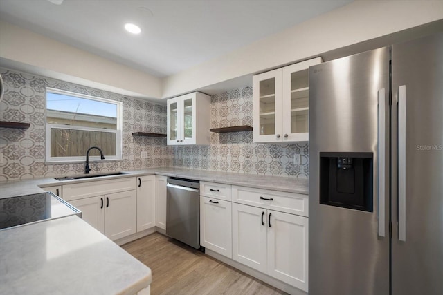 kitchen featuring appliances with stainless steel finishes, light countertops, white cabinetry, open shelves, and a sink