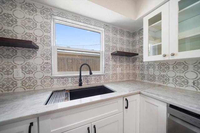 kitchen with light countertops, glass insert cabinets, white cabinets, a sink, and dishwasher