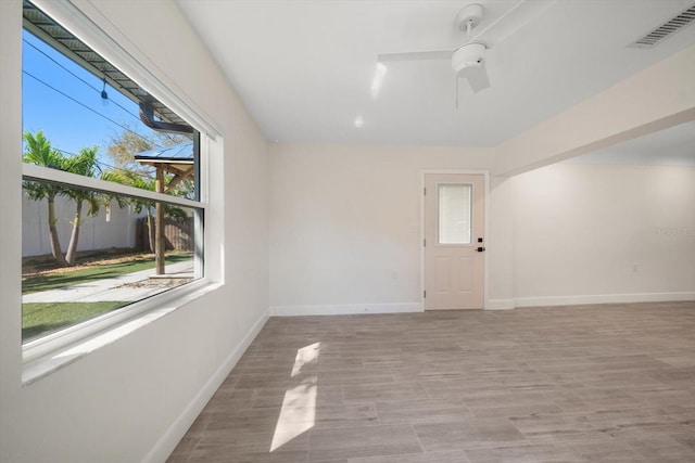 unfurnished room featuring a ceiling fan, light wood-type flooring, visible vents, and baseboards