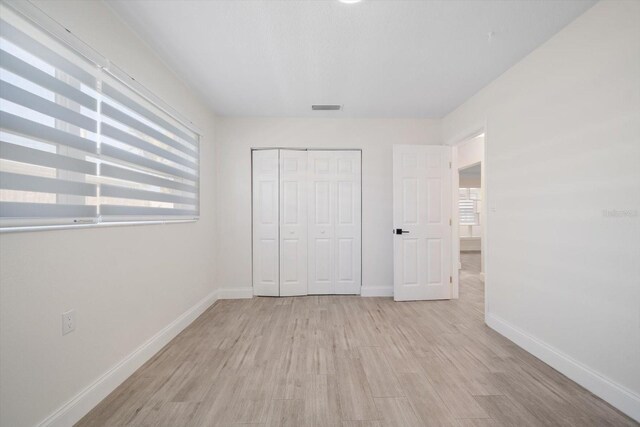 unfurnished bedroom featuring wood finished floors, visible vents, and baseboards