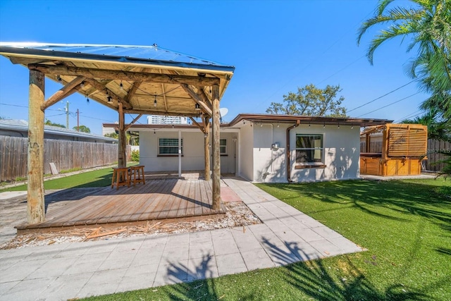 back of house featuring a deck, a lawn, fence, and stucco siding