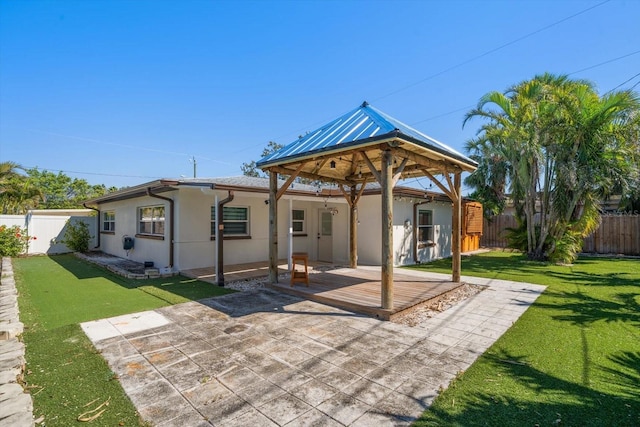 rear view of house with a gazebo, a fenced backyard, a lawn, and stucco siding