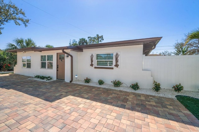 view of front of home featuring a patio area, fence, and stucco siding