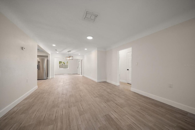 empty room with light wood-style flooring, visible vents, baseboards, and recessed lighting