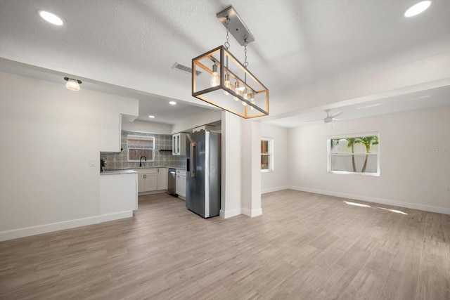 kitchen with tasteful backsplash, visible vents, open floor plan, stainless steel appliances, and a sink