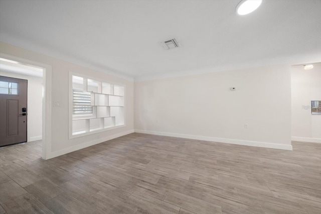 interior space with built in shelves, light wood finished floors, visible vents, and baseboards