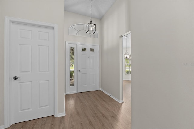 entrance foyer featuring light wood-style floors, baseboards, and a chandelier