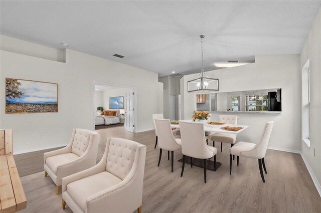 dining space featuring light wood finished floors, visible vents, baseboards, and an inviting chandelier