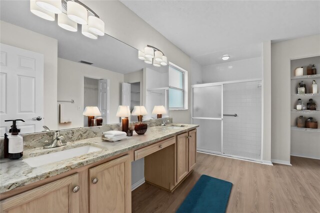 full bathroom featuring visible vents, a sink, a shower stall, and wood finished floors