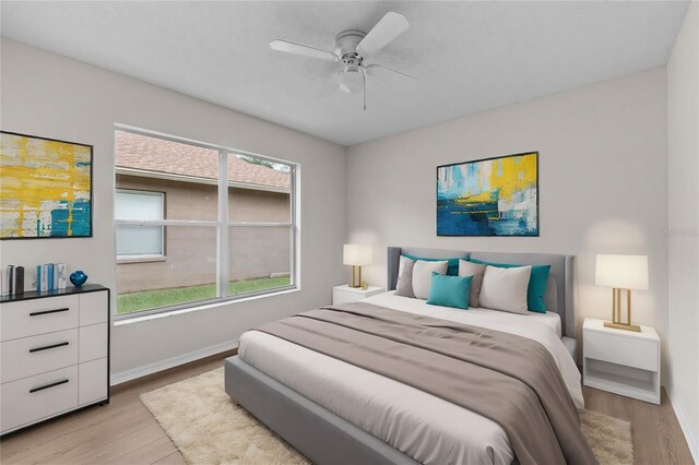 bedroom with light wood-style floors, multiple windows, ceiling fan, and baseboards