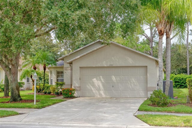 single story home with a garage, a front lawn, concrete driveway, and stucco siding