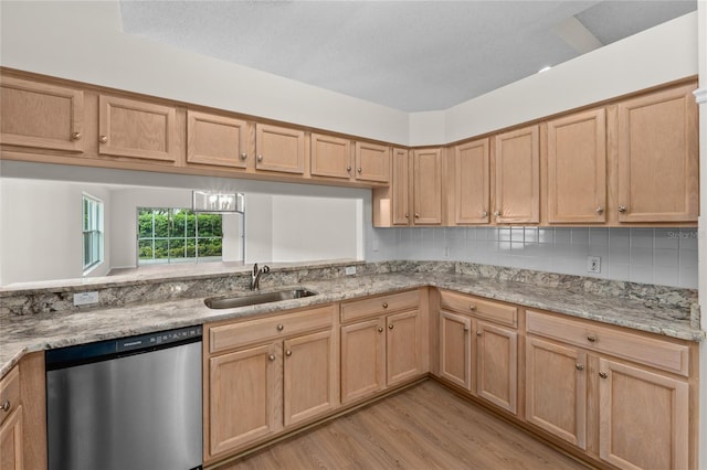 kitchen featuring light wood-style floors, dishwasher, a sink, and light stone countertops