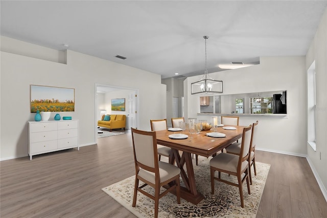 dining room with baseboards, visible vents, an inviting chandelier, and wood finished floors