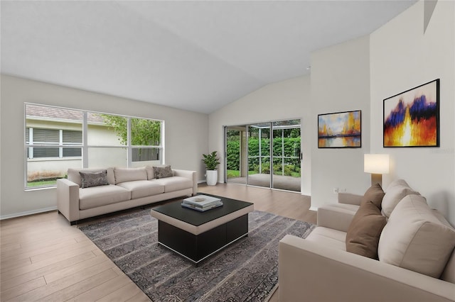 living area featuring a healthy amount of sunlight, vaulted ceiling, baseboards, and wood finished floors