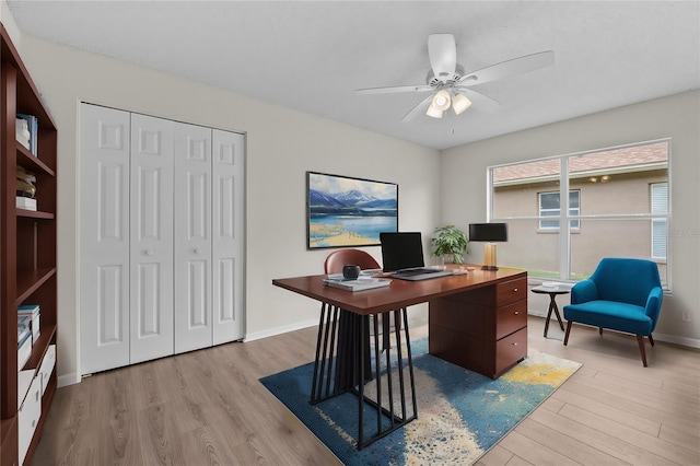 office featuring light wood-style floors, baseboards, and a ceiling fan