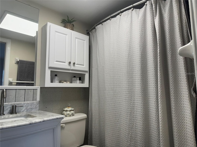 bathroom with curtained shower, vanity, and toilet