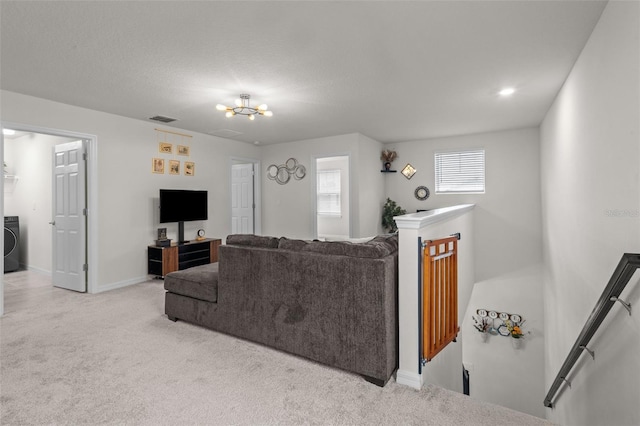 living room featuring light colored carpet, a textured ceiling, and washer / dryer