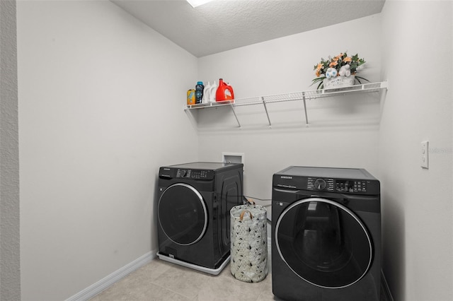 laundry room featuring light tile patterned flooring, separate washer and dryer, and a textured ceiling