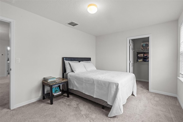 carpeted bedroom featuring a walk in closet, a closet, and a textured ceiling