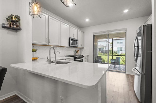 kitchen with white cabinetry, stainless steel appliances, kitchen peninsula, and decorative light fixtures