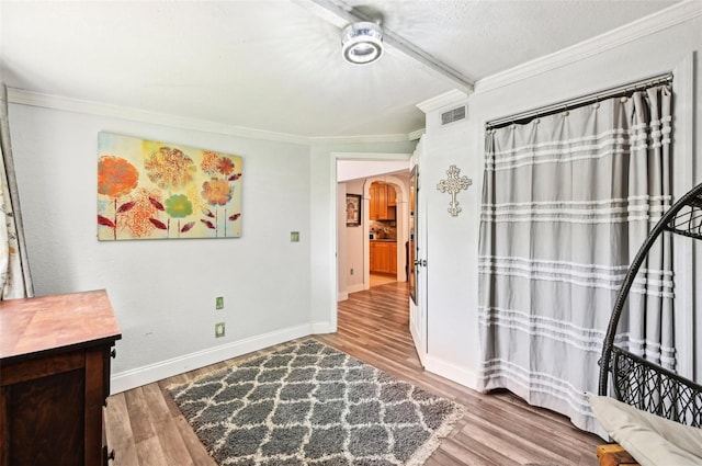 living area with a textured ceiling, ornamental molding, and hardwood / wood-style floors