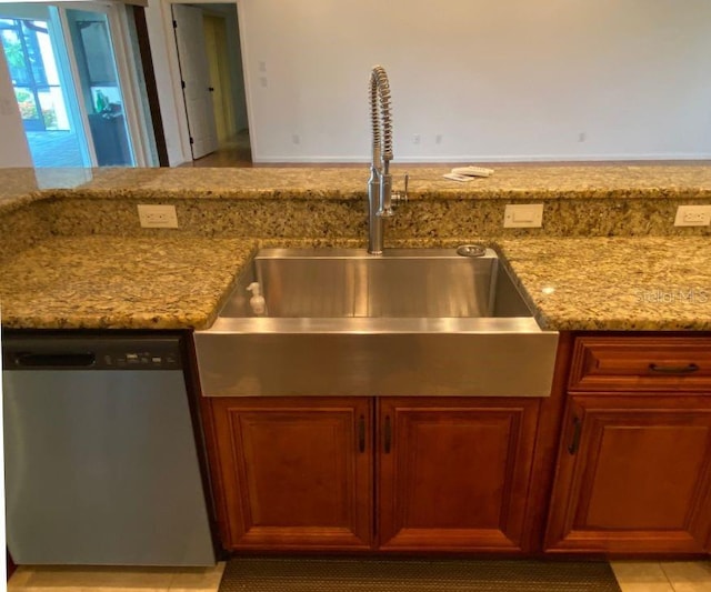 kitchen featuring dishwasher, light stone counters, and sink