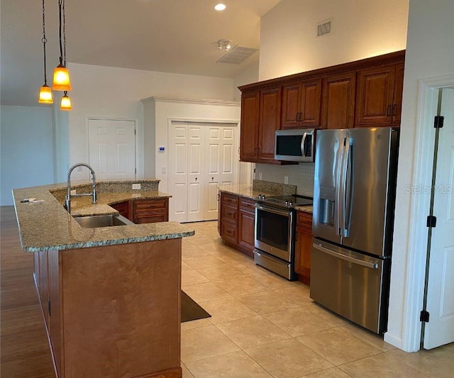 kitchen featuring a kitchen island with sink, sink, hanging light fixtures, appliances with stainless steel finishes, and lofted ceiling