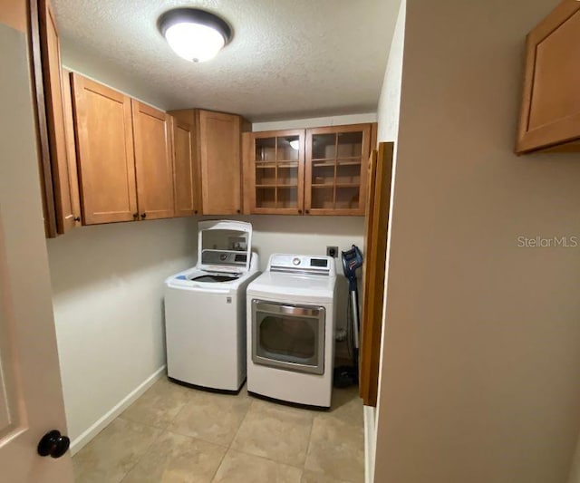 132 Peckham St SE, Port Charlotte, FL 33952 - washroom featuring baseboards, a textured ceiling, light tile patterned flooring, cabinet space, and washer and dryer