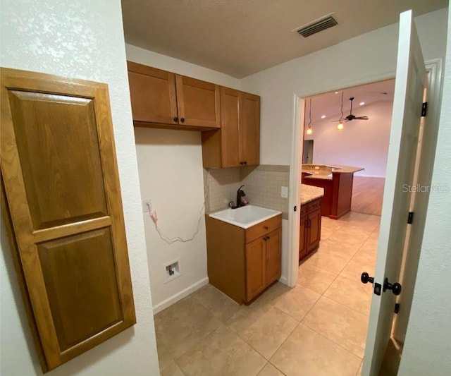 132 Peckham St SE, Port Charlotte, FL 33952 - kitchen featuring backsplash, a sink, brown cabinets, light tile patterned floors, and visible vents