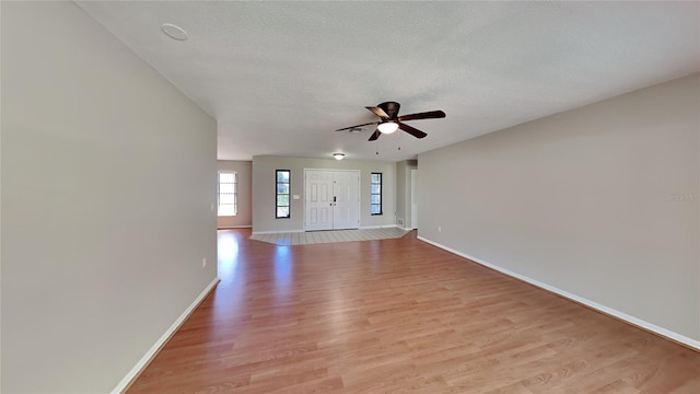 interior space with a textured ceiling, light wood-type flooring, and ceiling fan