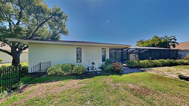 view of front of property with glass enclosure and a front lawn