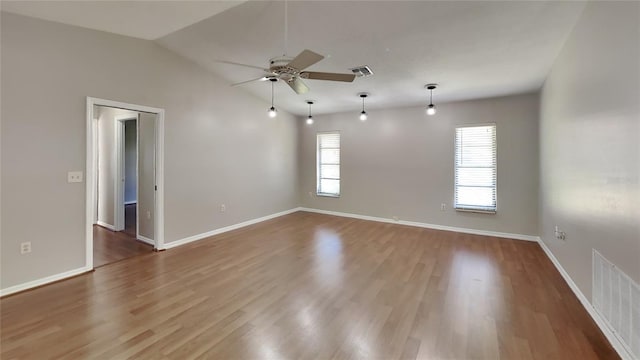 empty room with ceiling fan, lofted ceiling, and hardwood / wood-style flooring