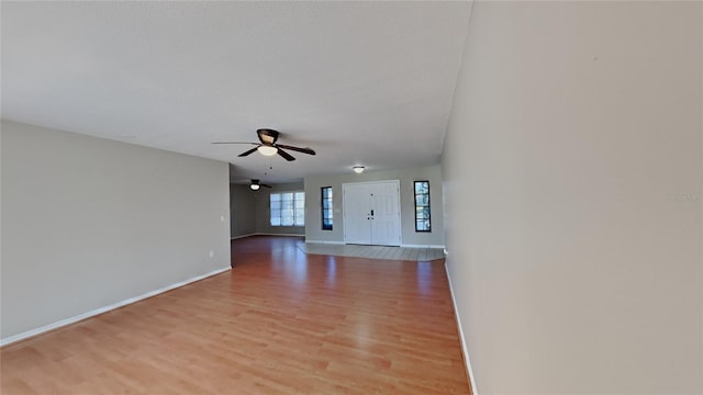 unfurnished living room with a ceiling fan, light wood-type flooring, and baseboards