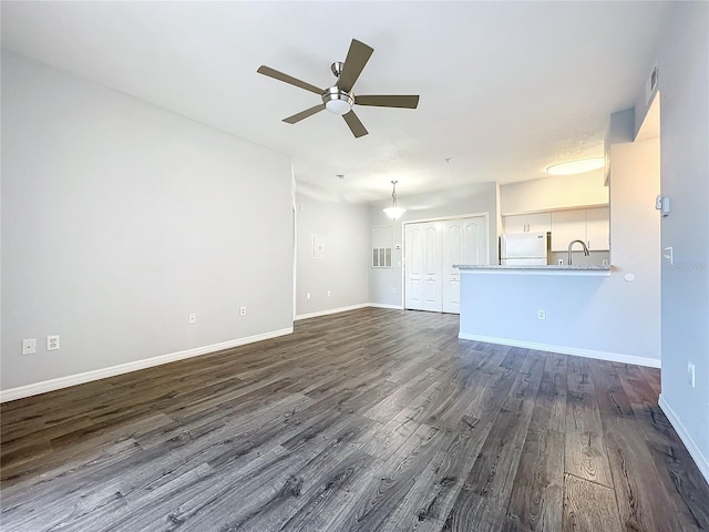 unfurnished living room featuring dark wood-type flooring and ceiling fan