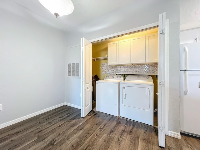 laundry area featuring separate washer and dryer, cabinets, and dark hardwood / wood-style floors