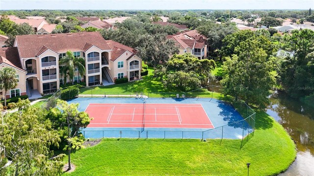 view of sport court with a lawn and a water view