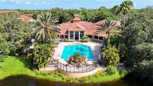 view of swimming pool featuring a water view, a patio area, and a yard