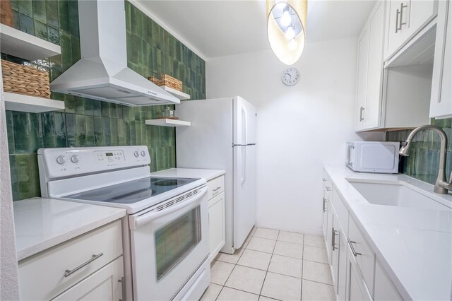 kitchen featuring white appliances, light tile patterned floors, sink, white cabinets, and wall chimney range hood