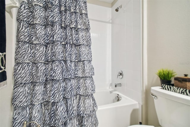 bathroom with tiled shower / bath combo and toilet