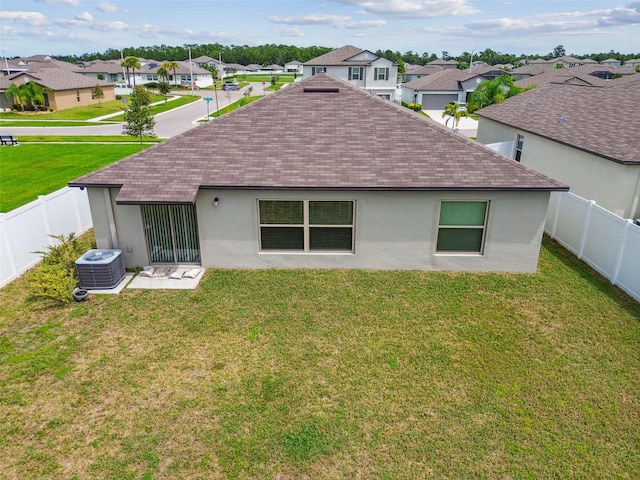 rear view of property featuring central AC and a lawn