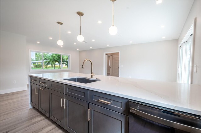 kitchen with light stone counters, pendant lighting, sink, stainless steel dishwasher, and light wood-type flooring