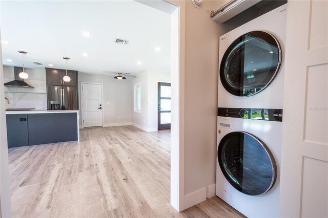 laundry room with stacked washer / dryer and light wood-type flooring